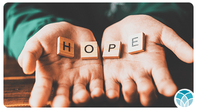 A person holding wooden blocks that spell out hope.