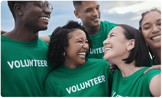 A group of people wearing green shirts and smiling.