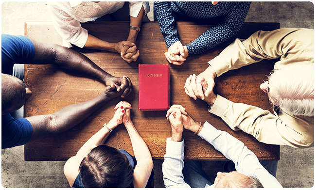 A group of people sitting around each other holding hands.